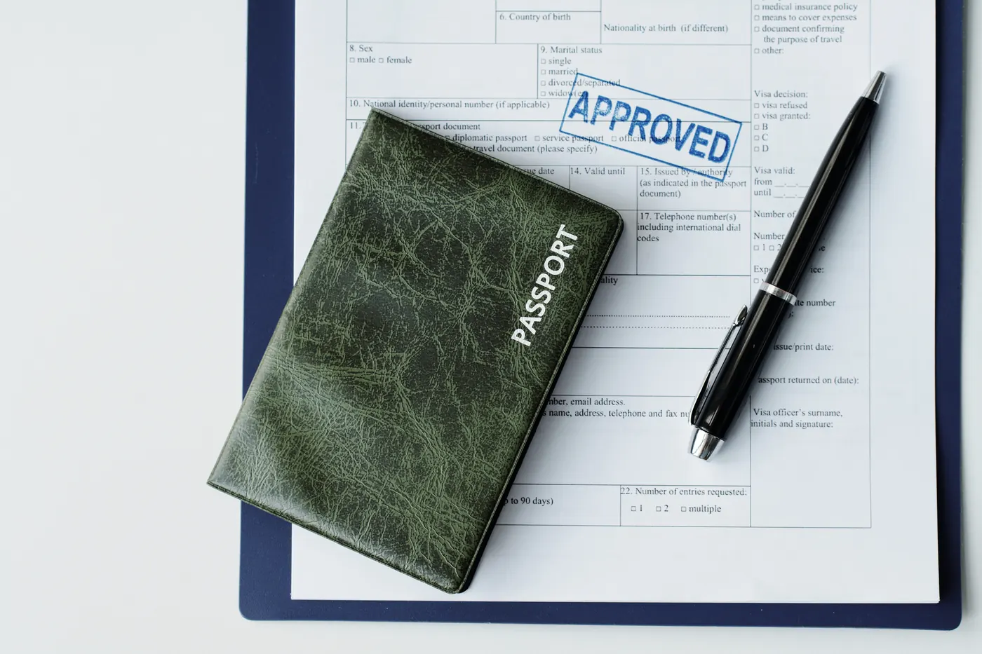 Topdown flat lay of passport in dark green leather cover, travel visa application paper with Approved stamp