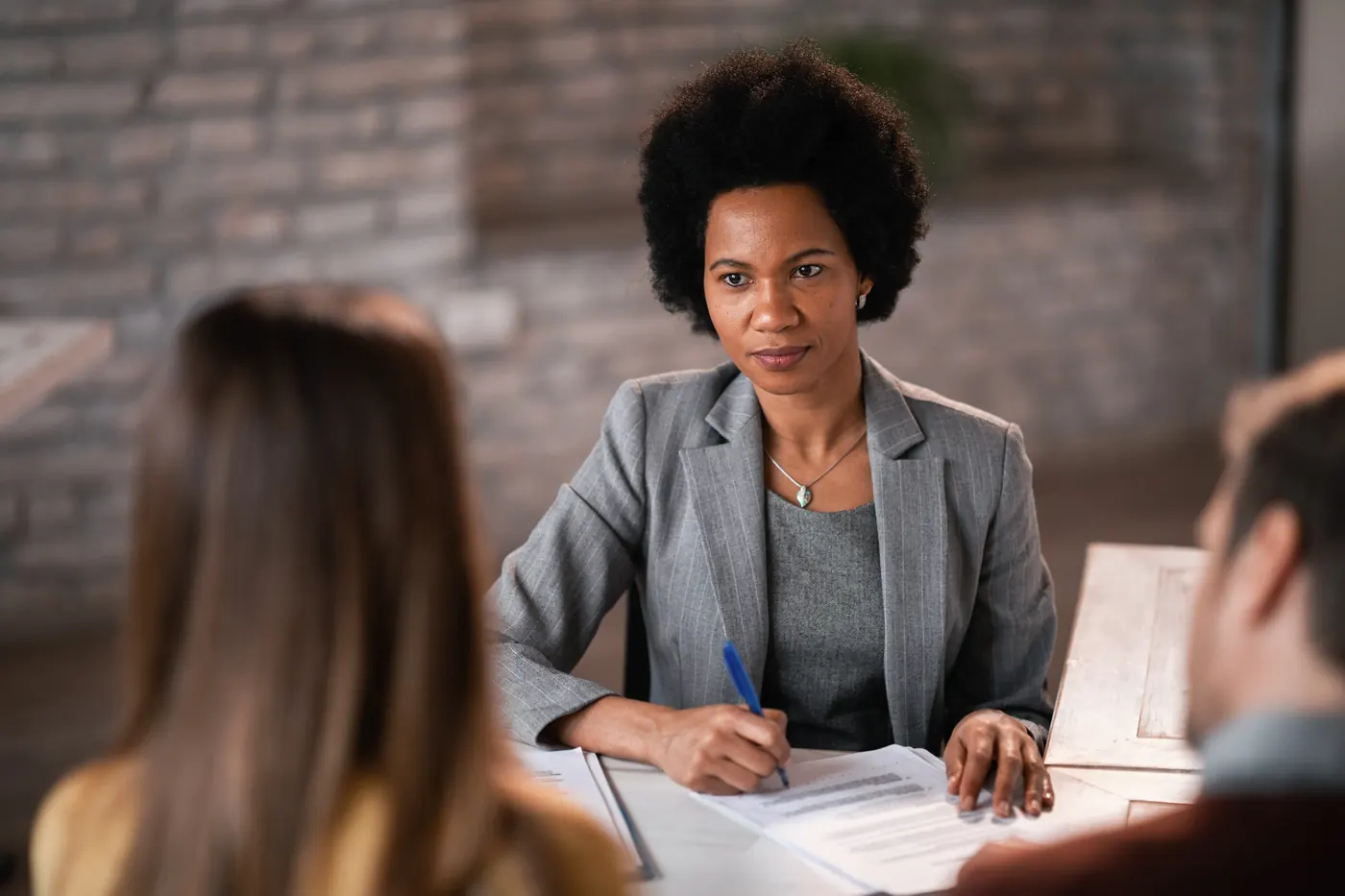 African American bank manager having an interview with her clients and filing paperwork during the meeting