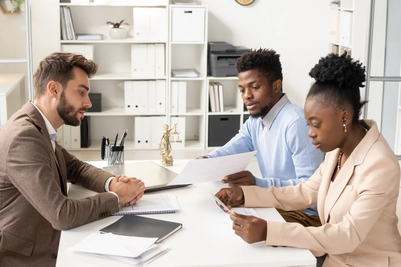 Young African woman reading paper while her husband consults with lawyer