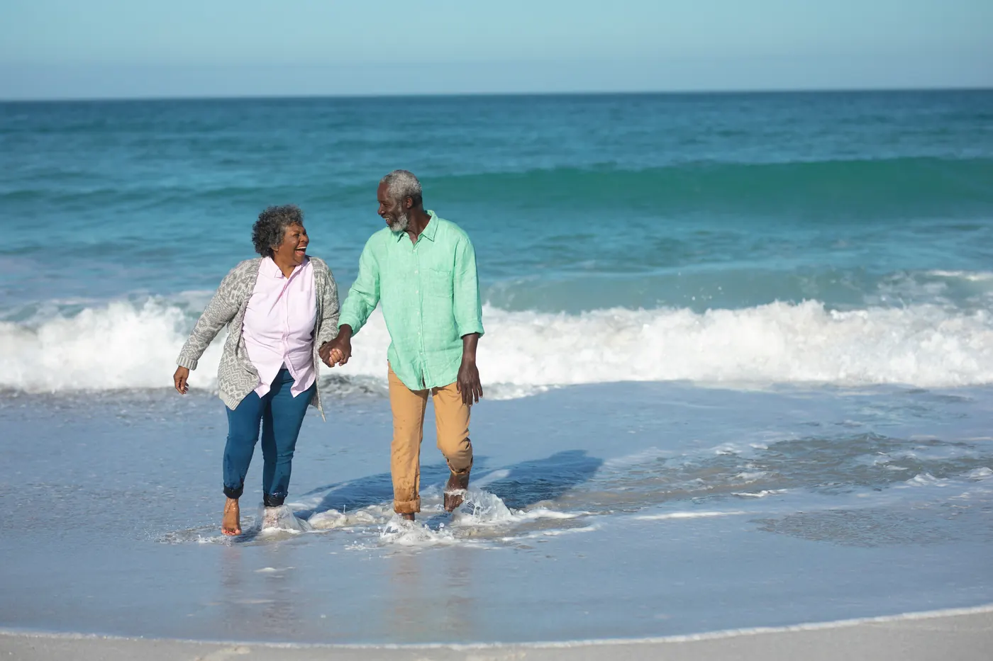 Senior African American couple paddling in shallow water on the beach