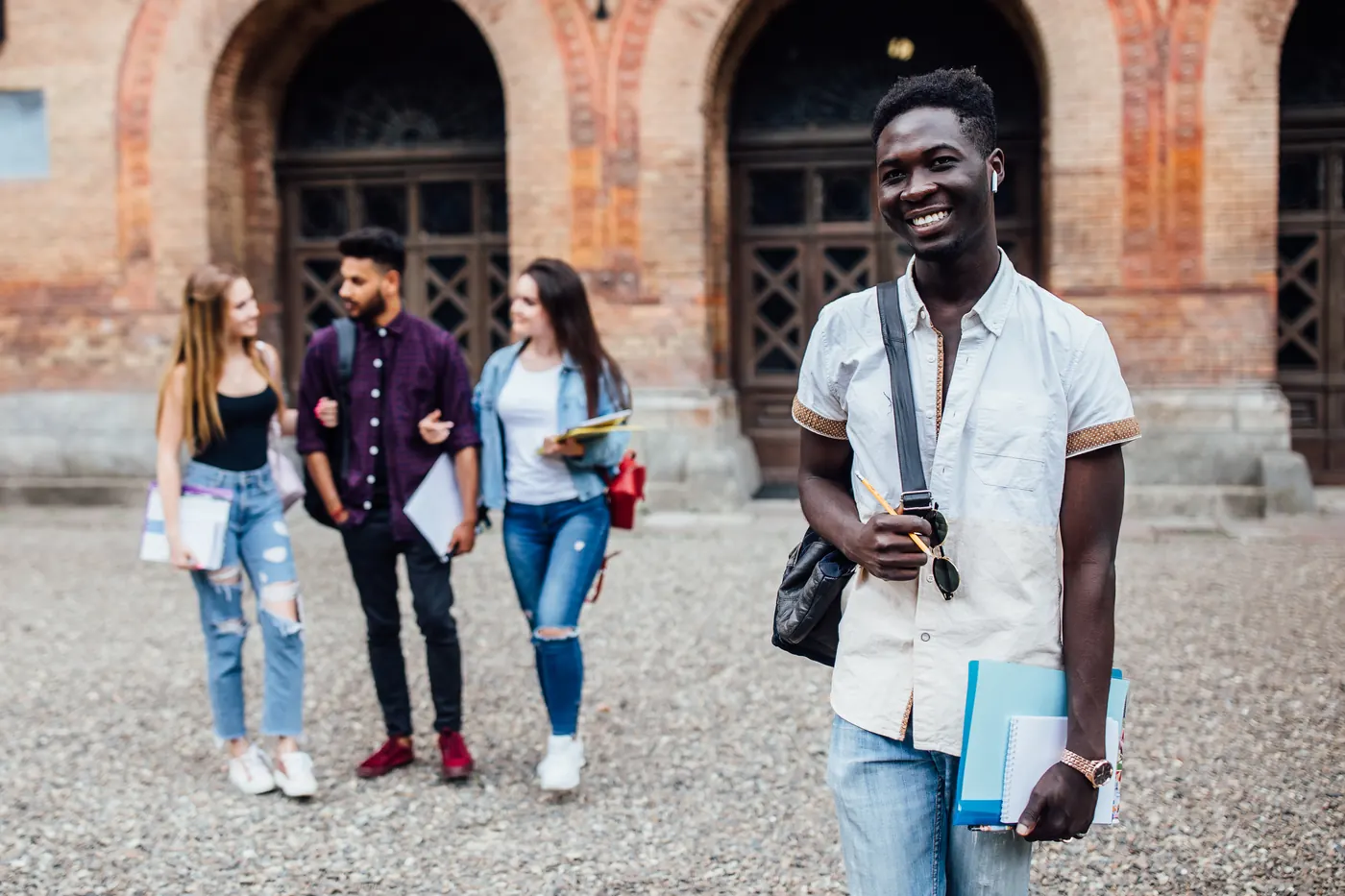 Smiling cheerful successful African student standing with books