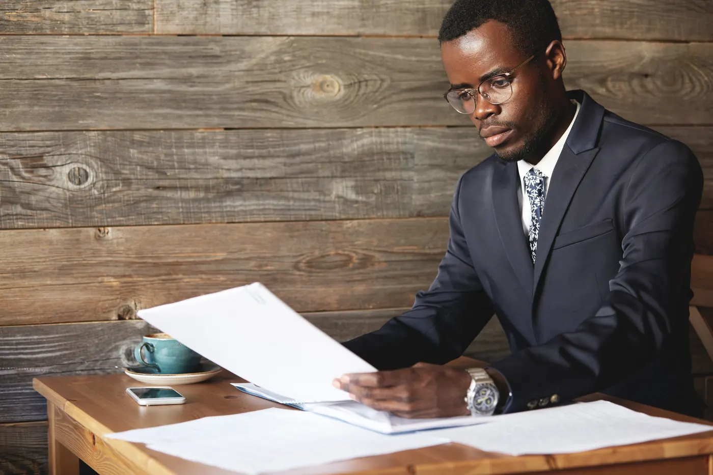Young African accountant wearing formal wear, holding documents, dealing with paperwork